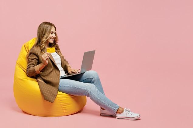 full body young fun employee business woman she wear jacket sit in bag chair us laptop pc computer hold credit bank card shopping online order delivery isolated on plain pastel light pink background.